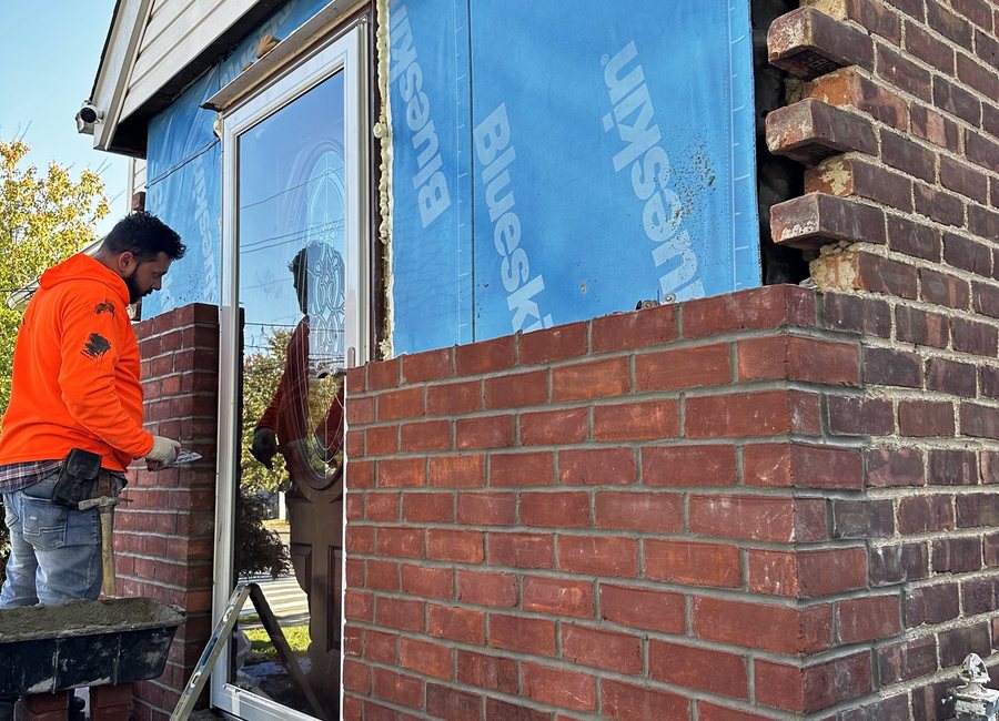 Worker repairing an exterior brick facade around a window
