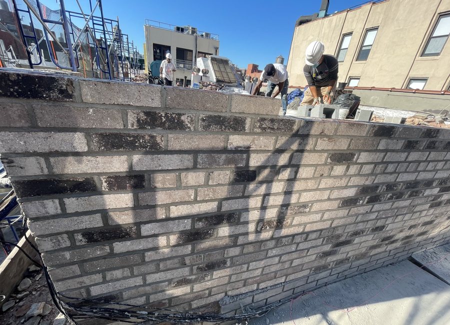 Workers on a roof repairing a parapet wall
